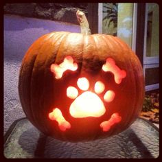 a carved pumpkin with paw prints on it's face and light in the middle