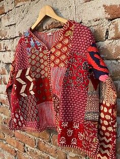 a red and white jacket hanging on a brick wall next to a wooden hanger