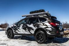 a black and white vehicle with skis on it's roof parked in the snow