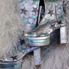 a pair of silver high heeled shoes with stars on the side and fur around them