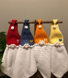 four knitted towels hanging on a clothes line with flowers in the corner and one is yellow, red, blue, and white