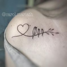 a woman's back shoulder with two birds and a heart tattoo on the left side