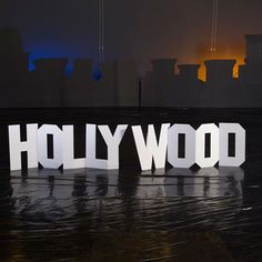 the word hollywood spelled out in white letters on a black surface with buildings in the background