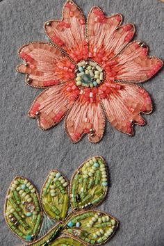 two embroidered flowers sitting on top of a piece of fabric next to each other,