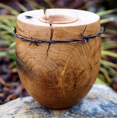 a wooden bowl with barbed wire around it on top of a rock in the woods