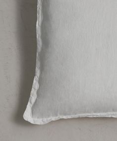 a white pillow with ruffled edges on a gray wall