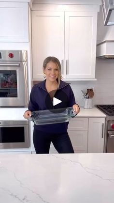 a woman standing in a kitchen holding an oven mitt