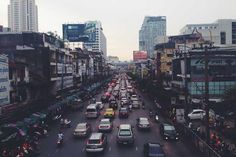 a city street filled with lots of traffic next to tall buildings on either side of the road