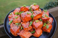 a black plate topped with salmon covered in sesame seeds