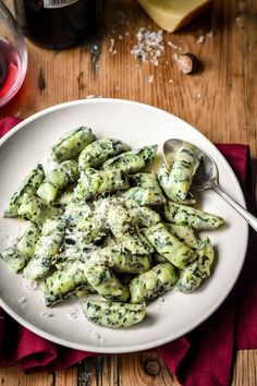 a white plate topped with pasta covered in pesto