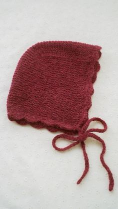 a crocheted hat with a knot on the side sitting on a white surface