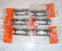 six screws are wrapped in plastic on the counter top, with orange tags around them