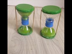 two green sand timers sitting on top of a wooden floor