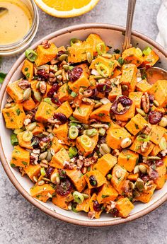 a bowl filled with sweet potato salad next to some oranges and other food items