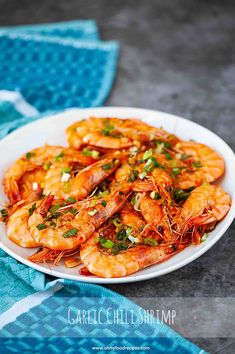 a white plate topped with cooked shrimp on top of a blue and white table cloth