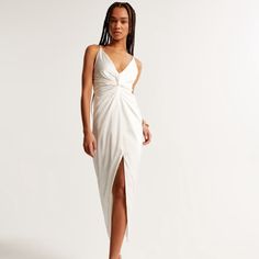 a woman is wearing a white dress with a slit on the side and one leg