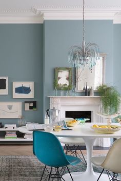 a dining room with blue walls and white table in front of the fireplace, surrounded by pictures on the wall