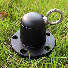 a black object sitting in the grass on top of it's base with a metal ring