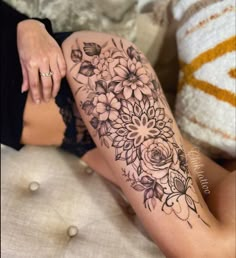 a woman's leg with flowers on it and her hand resting on the thigh