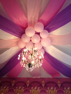 a chandelier hanging from the ceiling in a room decorated with balloons and streamers