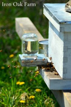 a beehive with some jars on it and bees in the grass near by