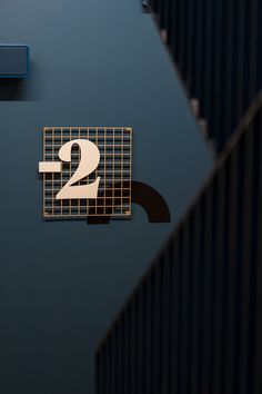 the number two sign is mounted on the wall next to some blue and black tiles