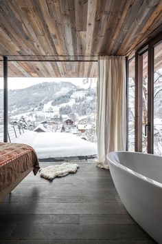 a large white bath tub sitting next to a window in a room filled with windows