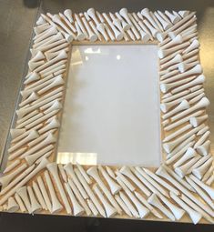 a white and brown frame sitting on top of a table next to a mirror with toothpicks in it