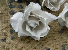 three white roses are sitting on a burlocked tablecloth with black dots