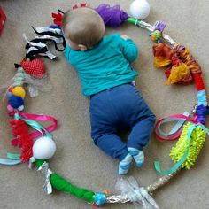 a baby is laying on the floor surrounded by toys and ribbons that are all around him