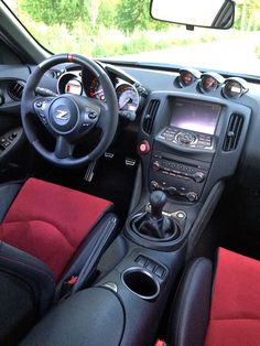 the interior of a car with red and black leather seats, steering wheel, dash board and dashboard