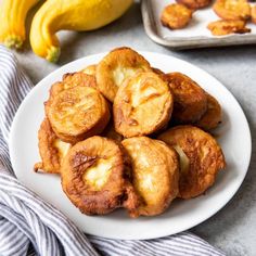 some food is sitting on a white plate and next to two pans with bananas