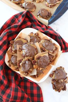 chocolate covered cookies sitting on top of a white plate next to a red and black checkered towel