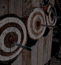 an old wooden target with two knives stuck in the bullseyes on it's side