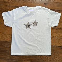 'Silver Star' Baby Tee Silver Star Baby Tee, Heavy Cotton, Iconic Slogan T-shirt, 90s Aesthetic Vintage Tee Trending Print Top  - 100% cotton - Classic fit - Runs true to size (refer to size chart) - Tear-away label - Y2K Vintage Streetwear Trending Fashion - Environmentally sustainable made-to-order system Baby tee's were popularised in the '90s, characterised by it's very short sleeves and slightly cropped body, creating a very flattering feminine shape. It originated from the skater/raver sce Silver Graphic Tee With Crew Neck, Silver Graphic Tee With Short Sleeves, Silver Cotton Top For Streetwear, Silver Cotton Tops For Streetwear, Silver Crew Neck Cotton T-shirt, Silver Cotton Crew Neck T-shirt, 90s Aesthetic Vintage, Star T Shirt, Slogan T Shirt