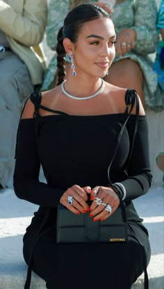 a woman sitting on the ground with her handbag in her other hand and people behind her