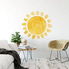 a living room with a white couch and yellow sun wall decal on the wall