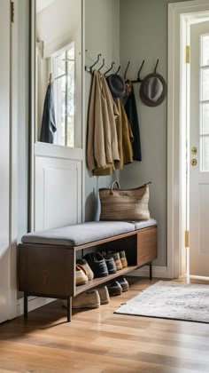 an entryway with shoes, coat rack and purse on the bench next to it