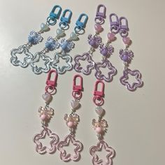 several different colored key chains with charms attached to them on a white surface, one is pink and the other is blue