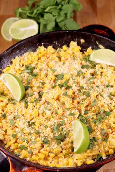 a skillet filled with corn and topped with limes