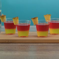 four shot glasses filled with different colored drinks