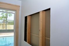 an unfinished room with a pool in the back ground and a window on the far wall