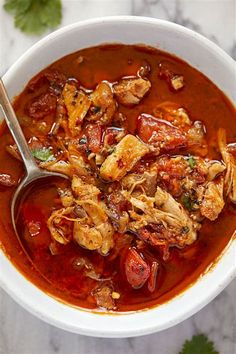 a white bowl filled with chicken and tomato soup