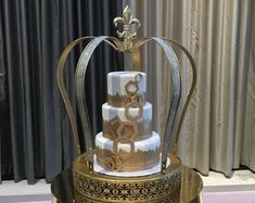 a three tiered cake sitting on top of a metal stand with gold trimming