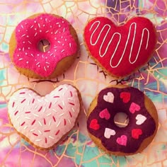 three donuts with pink frosting and sprinkles in the shape of hearts