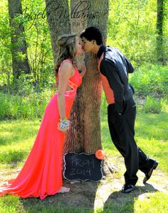 a man and woman kissing in front of a tree