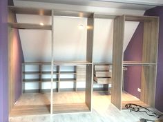 an empty room with wooden shelves and purple walls