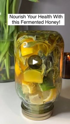 a glass jar filled with sliced lemons and herbs