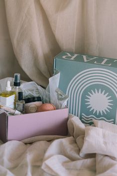 an open box on top of a bed next to some towels and other things in it