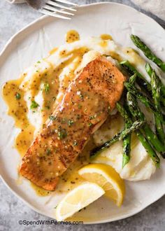 a white plate topped with fish and asparagus